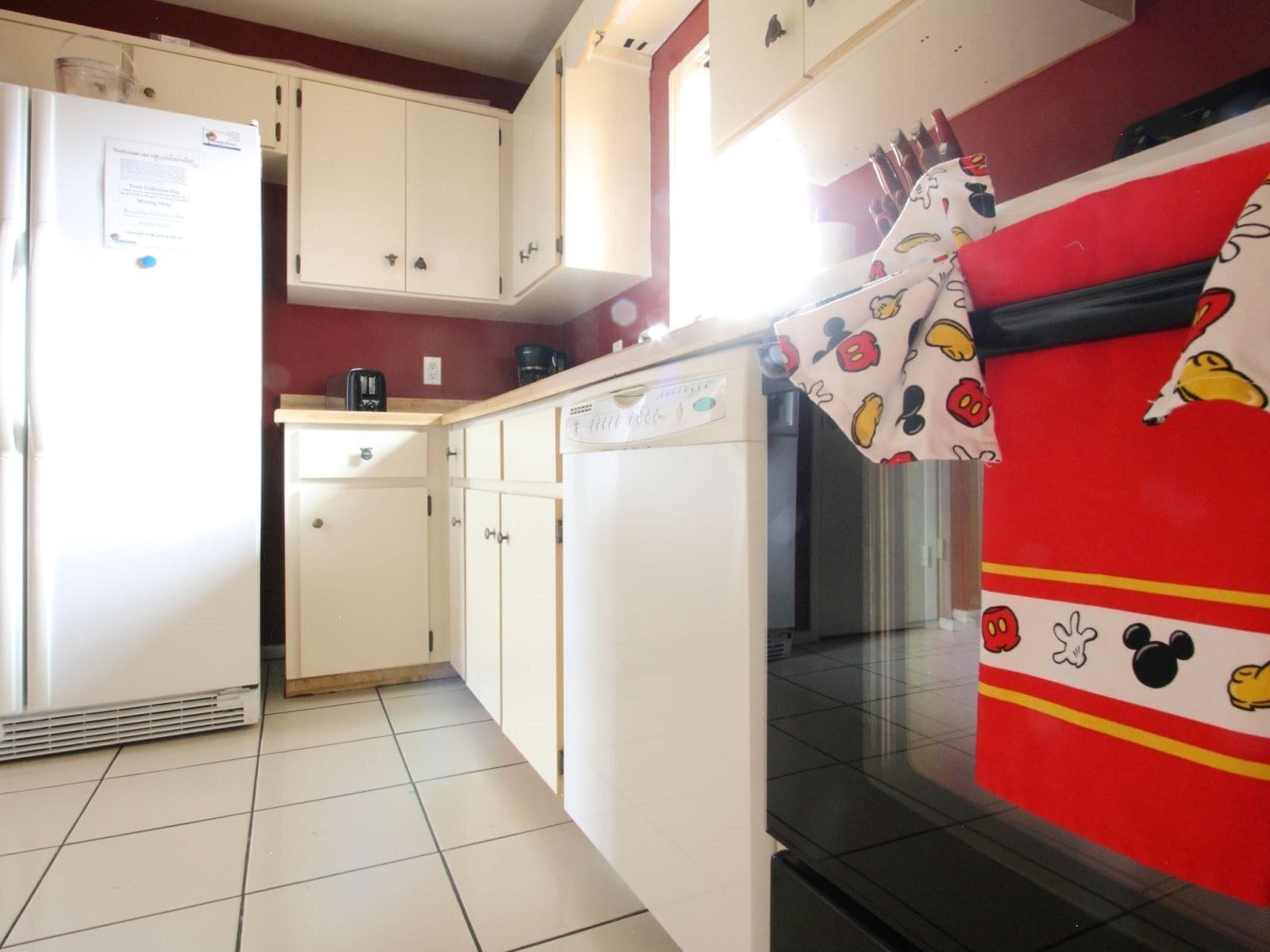 Una cocina con armarios blancos, un refrigerador, un lavavajillas y un microondas.