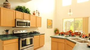 A kitchen with wooden cabinets, a stainless steel stove, a microwave, and a large window providing natural light. - 6 Bed 2525 (Kissimmee)
