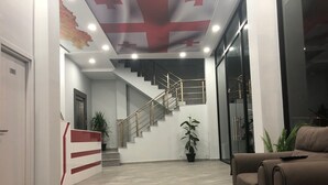 Een moderne lobby met een trap, een receptiebalie en een bank.