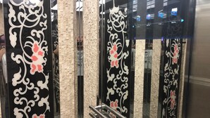 Een moderne lift met decoratieve zwart-wit bloemmotieven op de wanden.