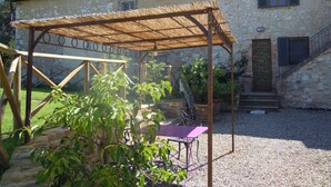 Un bâtiment en pierre doté d’un patio couvert, d’un escalier et d’une table avec des chaises.