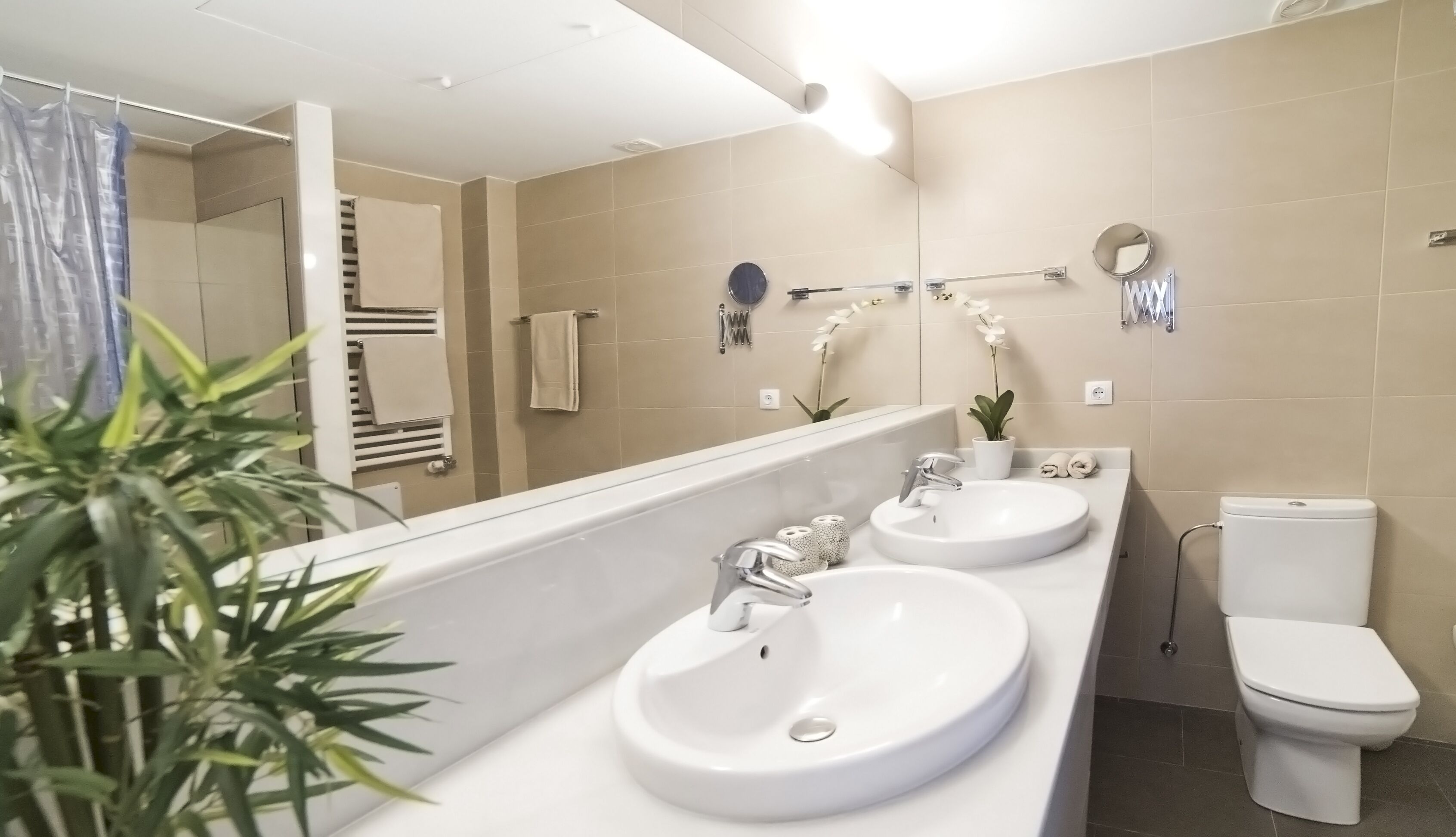 Un baño moderno con dos lavamanos, un inodoro y un espejo grande.