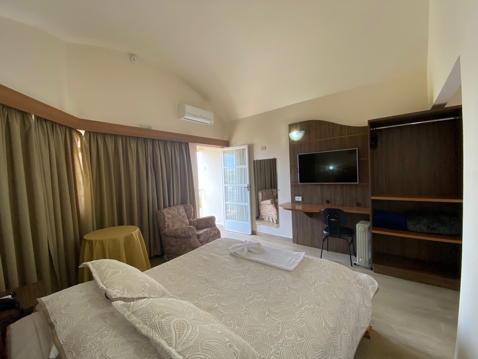 Een hotelkamer met een bed, bureau, stoel, televisie en kledingkast.