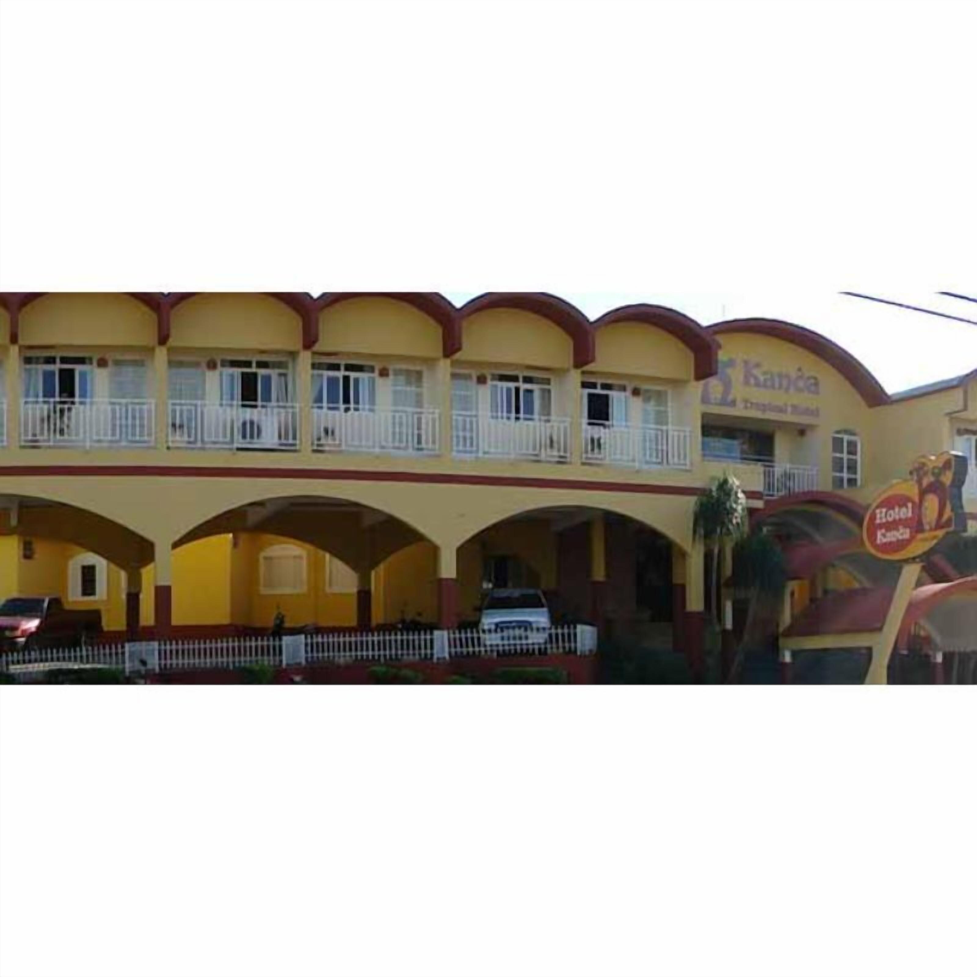 A hotel with a yellow facade, multiple balconies, and a sign indicating it is a hotel.