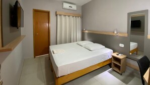A bedroom with a bed, bedside table, mirror, and a television mounted on the wall. - Kanoa Hotel (Santo Antônio da Platina)