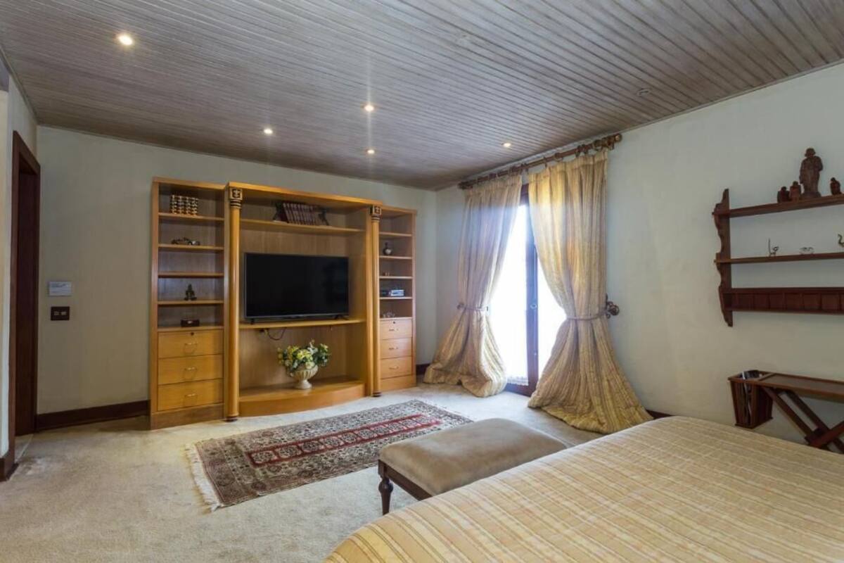 A bedroom with a bed, a TV, a wardrobe, and a small table.