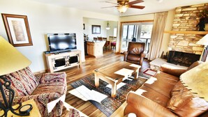 Una sala de estar con televisor, sofá, mesa de centro y chimenea.