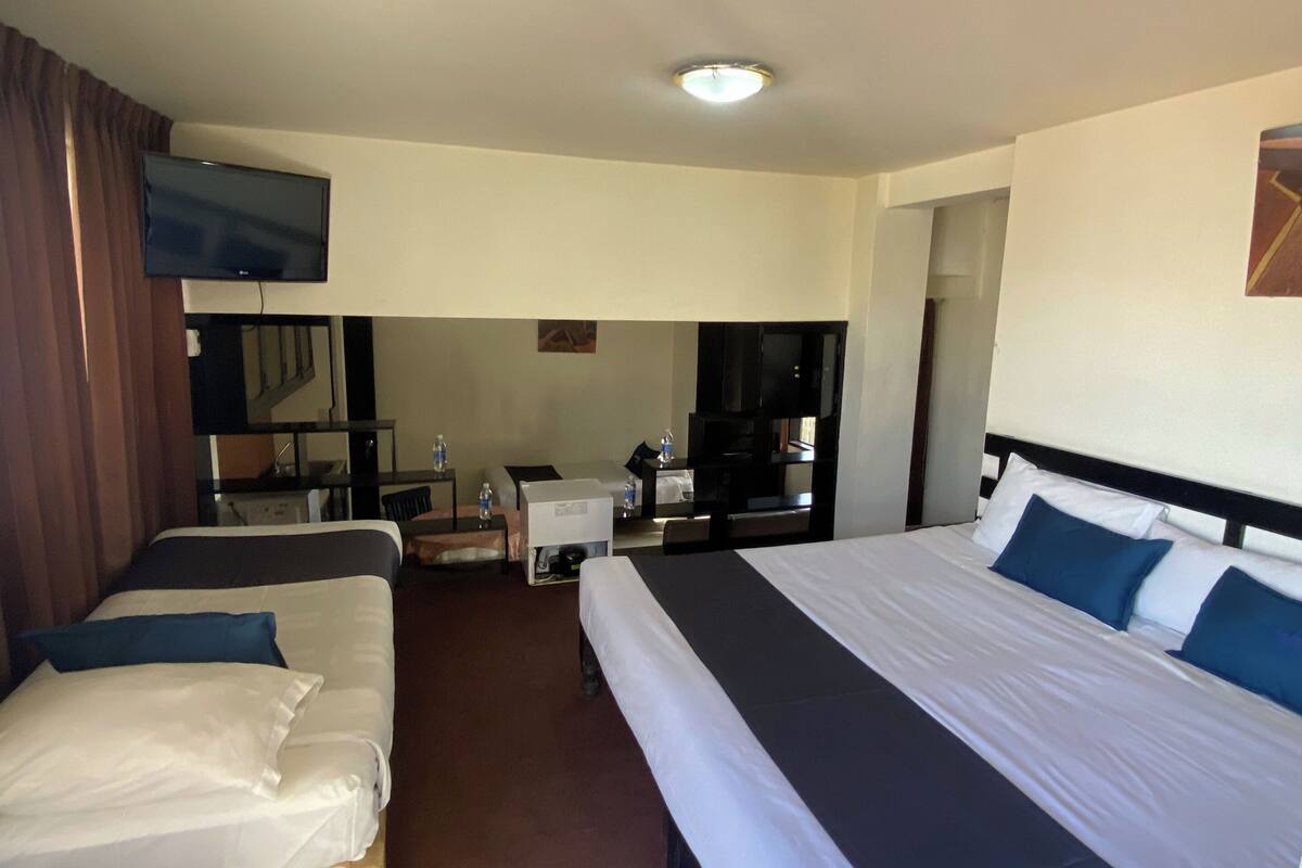 Une chambre d’hôtel avec deux lits, une télévision, un bureau et une chaise.