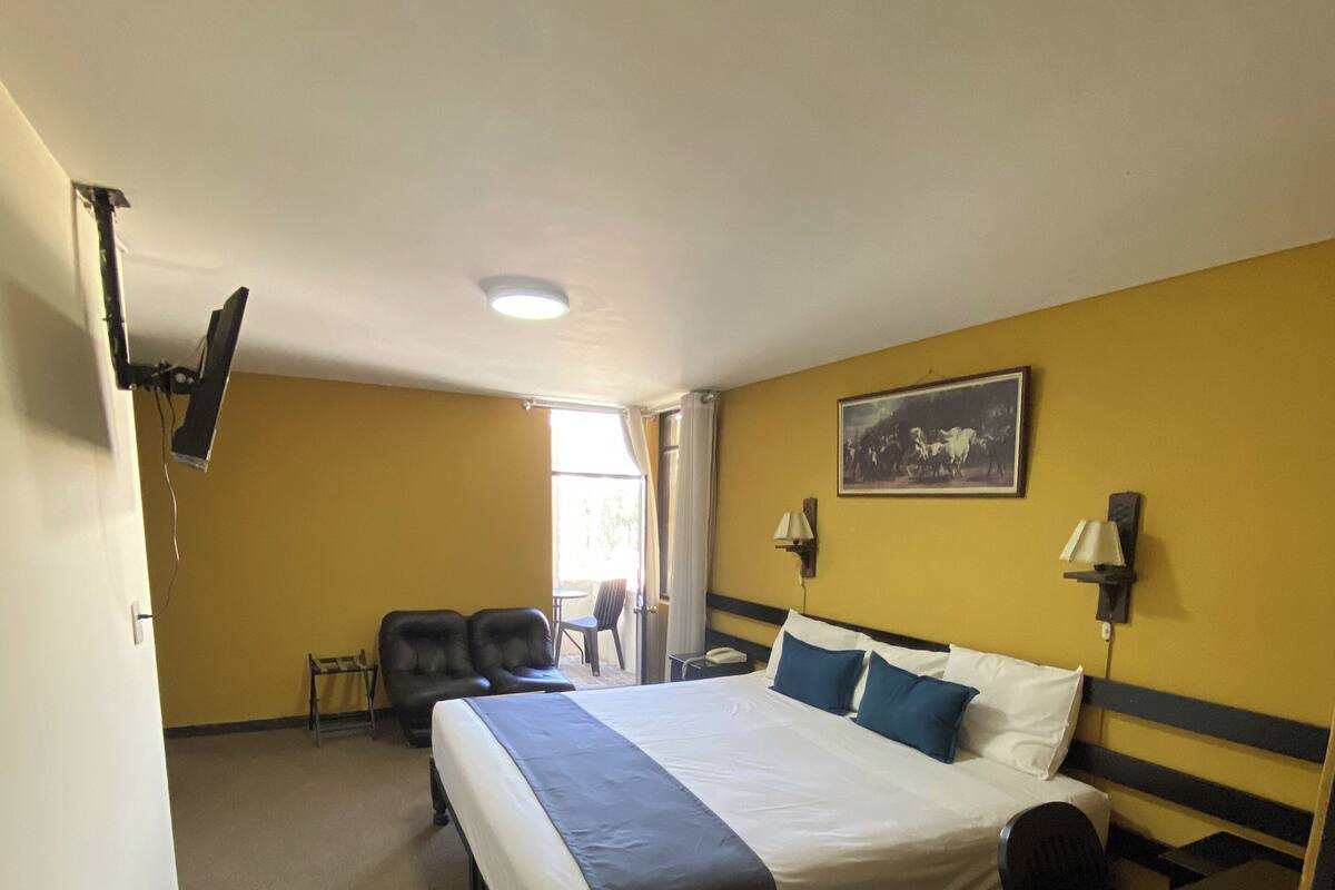 Une chambre d’hôtel avec un lit, un bureau, une chaise et une fenêtre.