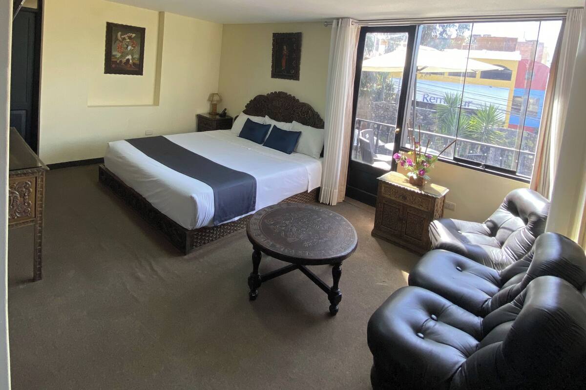 Une chambre à coucher avec un lit, un canapé, une petite table et une fenêtre donnant sur un beau paysage.
