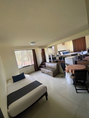 Habitación de hotel con cama, sofá, mesa de comedor y cocina.