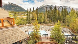 A resort with a pool, outdoor seating, and a mountain backdrop. - Mountain Luxe (Canmore)