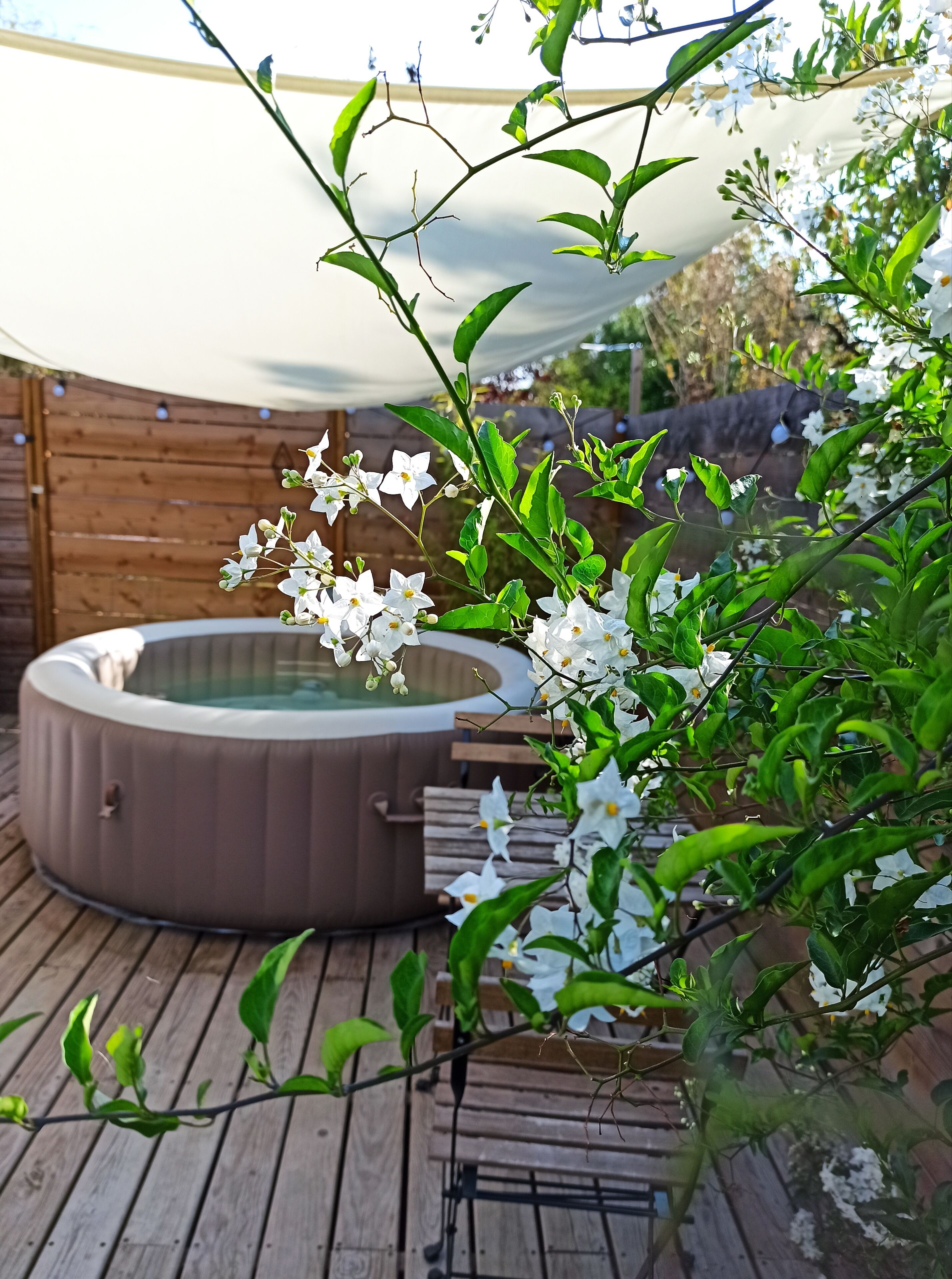 Un jacuzzi en una terraza de madera con un toldo.
