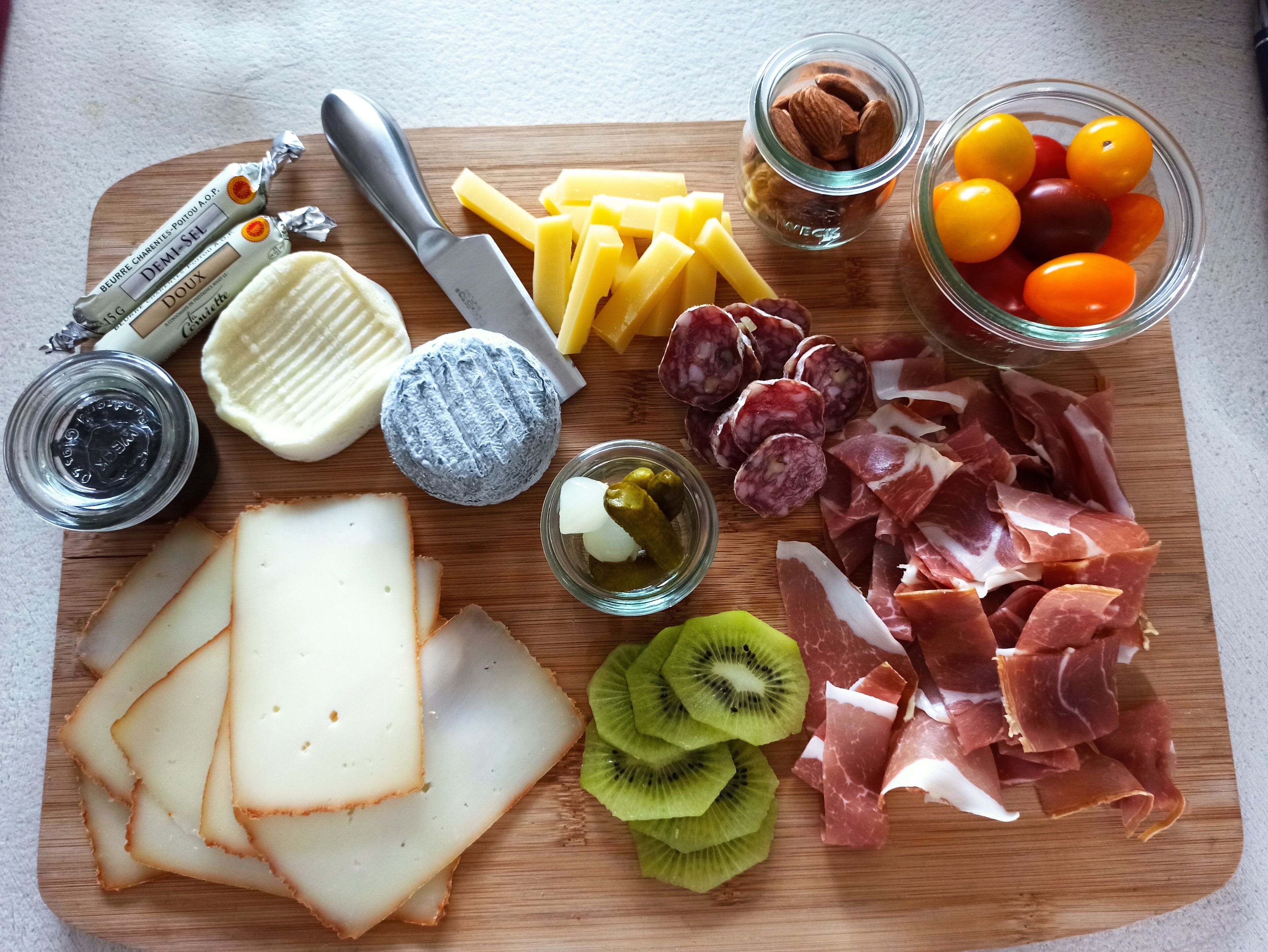 A variety of cheeses, cured meats, and fruits on a wooden board.
