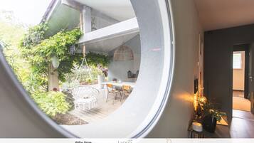 A circular window view of a modern kitchen with a dining area, featuring a hanging light fixture and a potted plant.