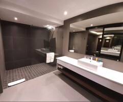 Un baño moderno con un espejo grande, un tocador blanco y una zona de ducha.