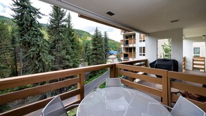 Uma varanda com vista para uma área arborizada e um edifício ao fundo.