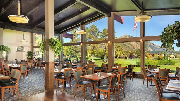 A restaurant with wooden tables and chairs, large windows offering a view of a golf course and mountains. - 1BD/Flagstaff w/Full Kitchen, W/D, Sleeper Sofa & Amazing Amenities!! (Flagstaff)