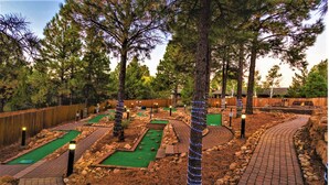 A miniature golf course with multiple lanes, surrounded by trees and wooden fencing. - 1BD/Flagstaff w/Full Kitchen, W/D, Sleeper Sofa & Amazing Amenities!! (Flagstaff)