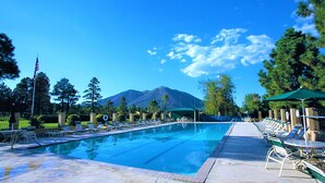 A swimming pool with lounge chairs and umbrellas, surrounded by trees and a mountain in the background. - 1BD/Flagstaff w/Full Kitchen, W/D, Sleeper Sofa & Amazing Amenities!! (Flagstaff)