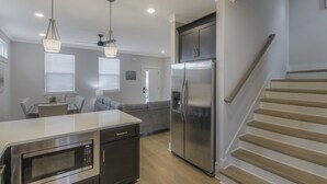 Une cuisine moderne équipée d’appareils électroménagers en acier inoxydable, un coin repas avec une table et des chaises, et un escalier menant à un autre niveau.