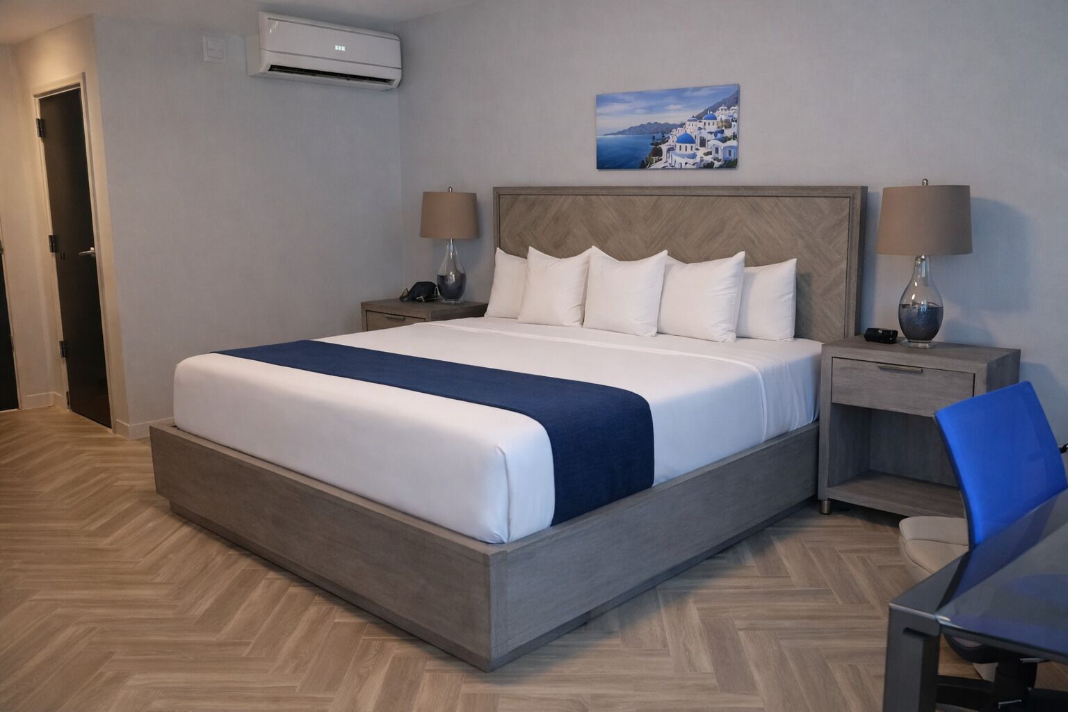 A hotel room with a large bed, two bedside tables, a desk, and a chair.