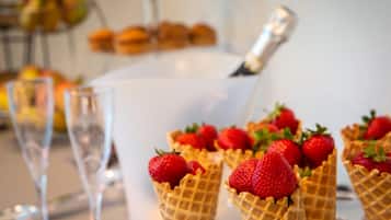A dessert table with waffle cups filled with strawberries and a champagne bottle.