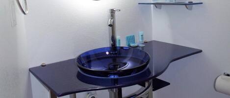 A bathroom with a round mirror, a blue sink, and a towel rack.