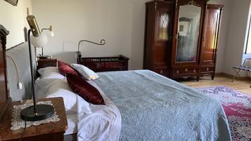 Un dormitorio con una cama, un armario de madera, una mesita de noche con lámpara y una silla.