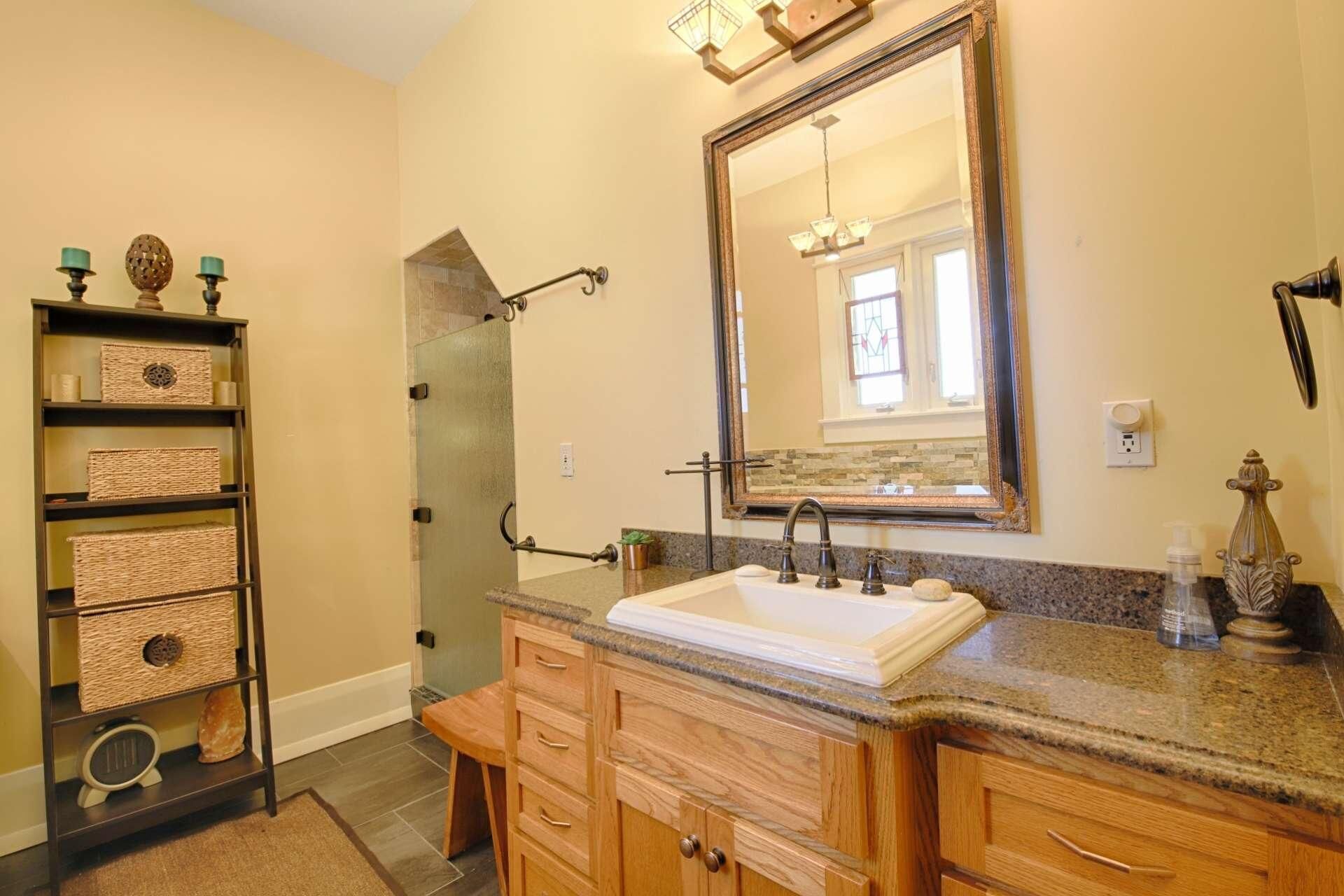 A bathroom with a sink, vanity, and a large mirror. There is a shelf with baskets and a small clock.