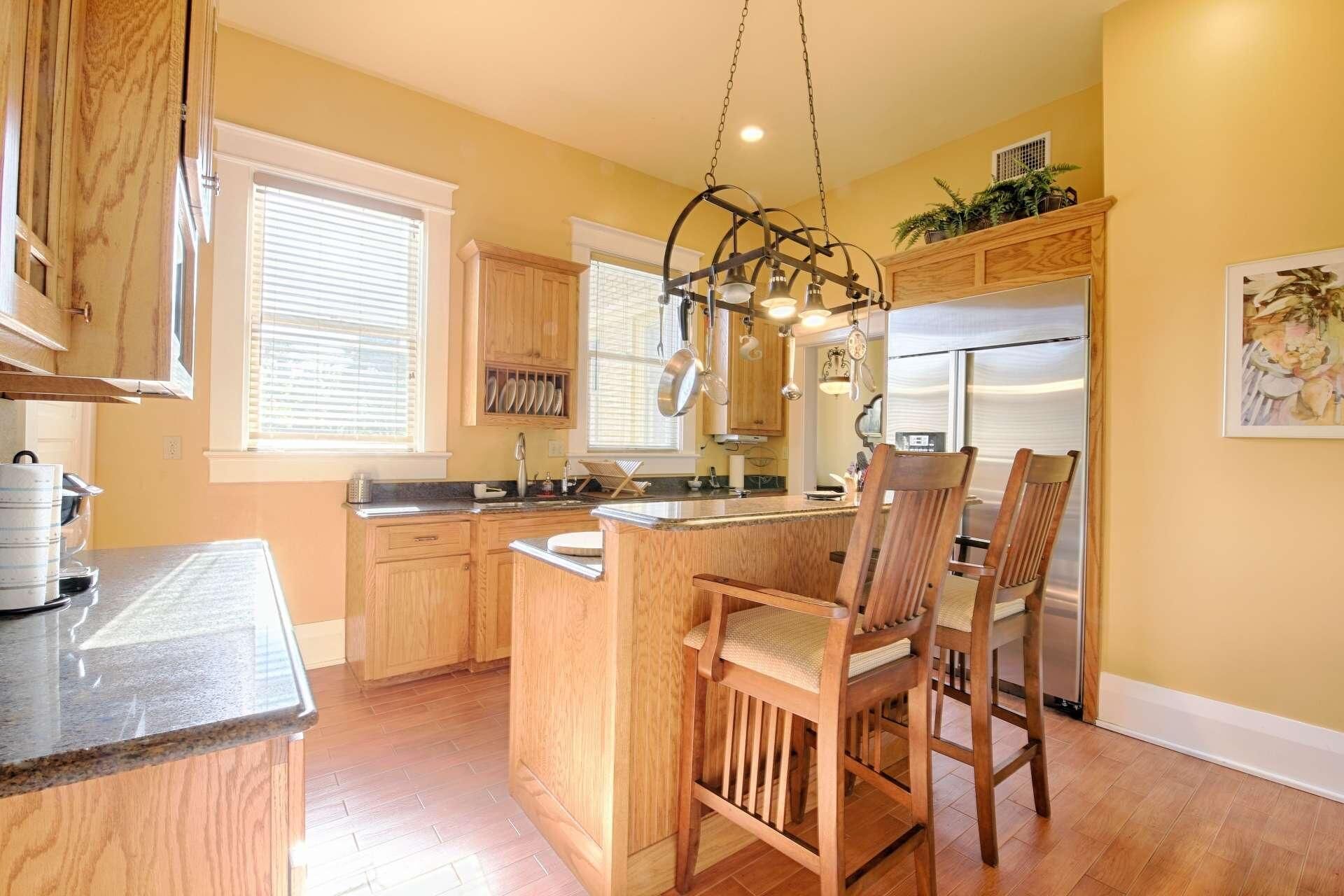 A kitchen with wooden cabinets, a central island, and a hanging light fixture.