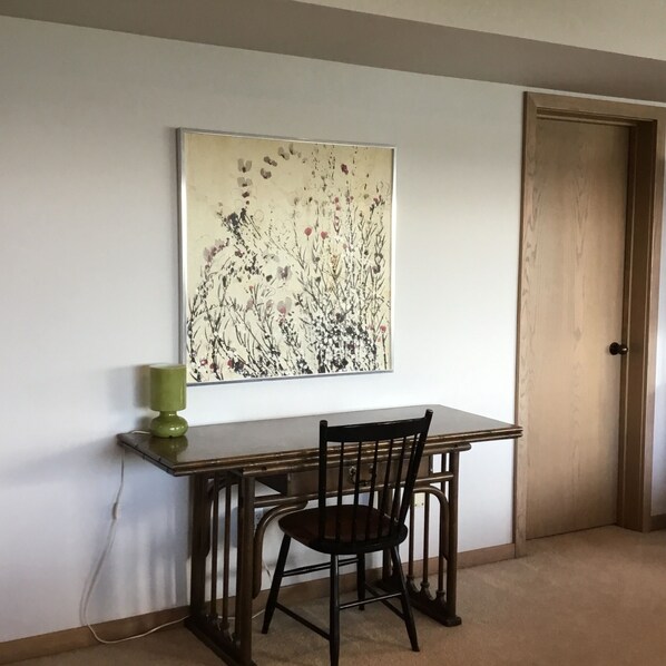 A dining area with a table, chairs, and a wall-mounted artwork.