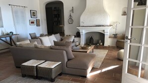 A living room with a sofa, a fireplace, and a door. - Atmospheric villa with nice sea view in a quiet green area (La Croix-Valmer)
