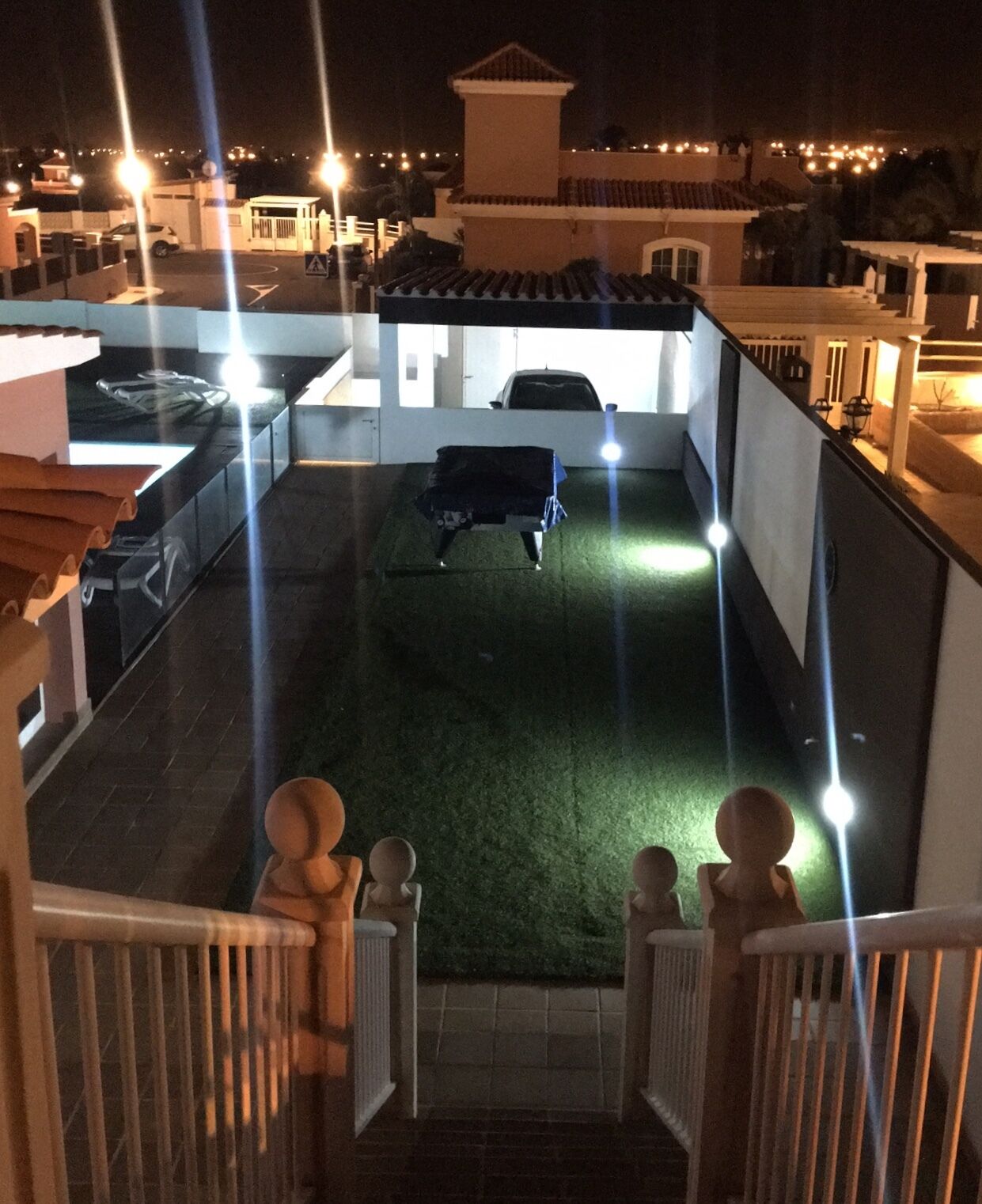 Une terrasse sur le toit avec une pelouse verdoyante, une voiture et un bâtiment doté d’un toit en tuiles.