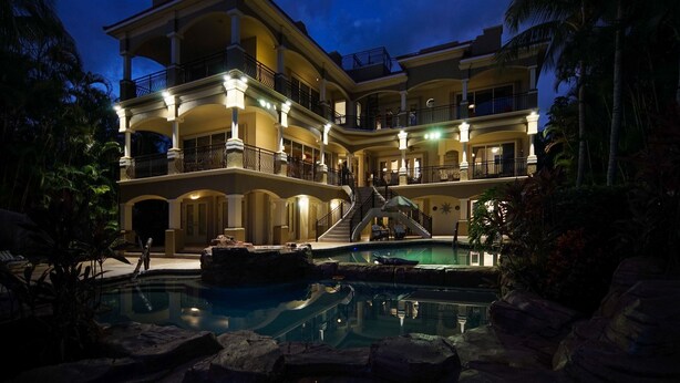 Un hotel de varios pisos con piscina, balcones y una escalera que conduce a los pisos superiores.