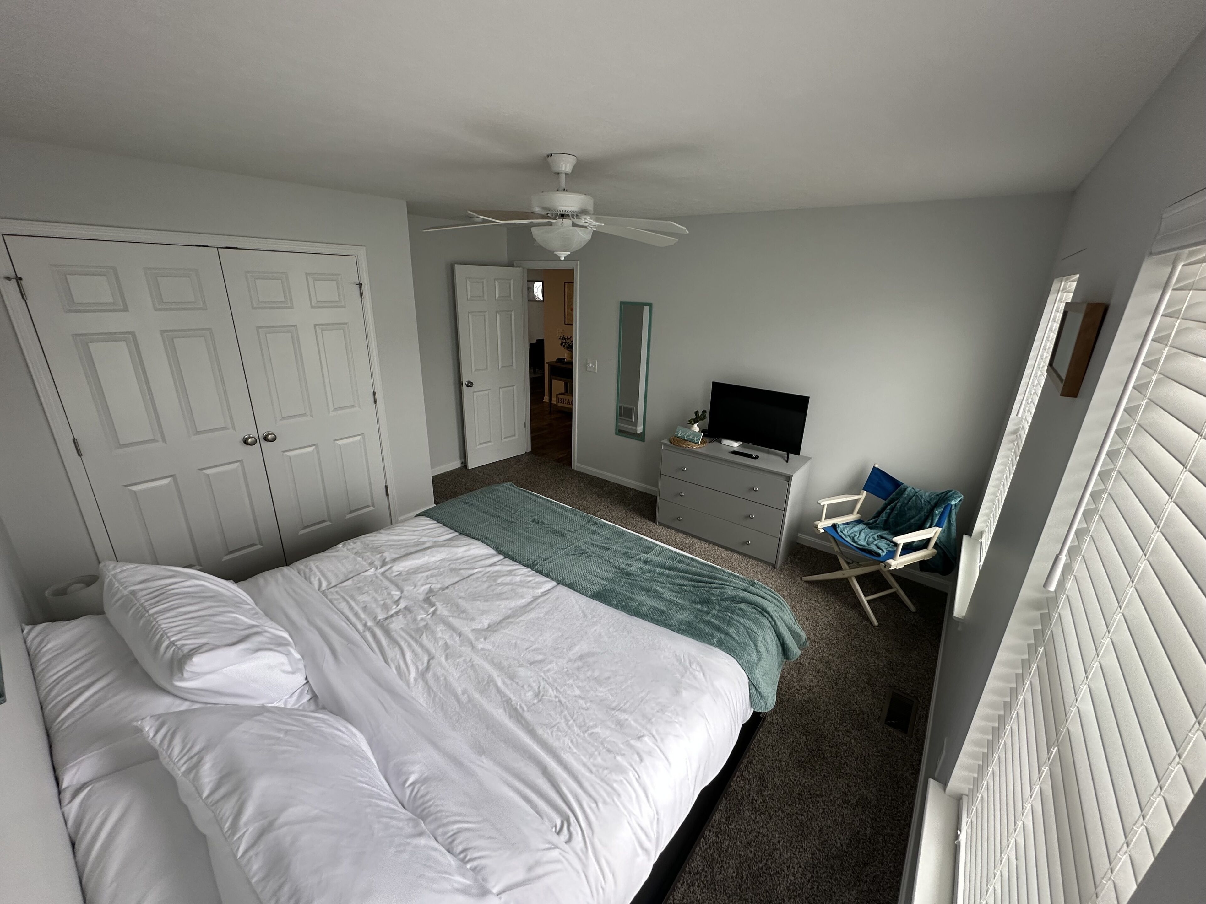 A bedroom with a bed, a dresser, a television, and a chair.
