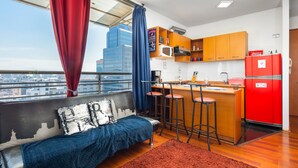 A modern apartment with a city view, a kitchenette, a sofa, and a dining area with stools. - Best Location in Santiago, Chile! Great View & Full Equiped Apartment! (Santiago)
