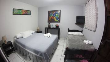 A bedroom with two beds, a TV, and artwork on the walls.