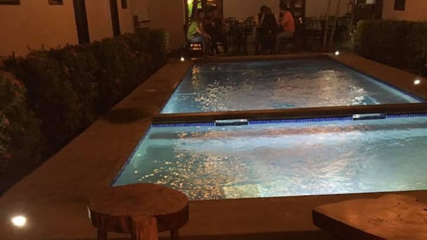Zona de piscina con un brasero al frente y una piscina al fondo.