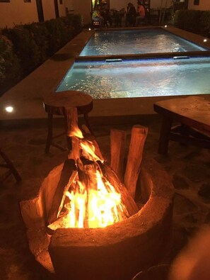 A pool area with a fire pit in the foreground and a pool in the background. - Hotel Don Al (Granada)