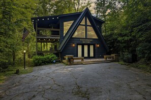 Une cabane en bois dotée d’un balcon, une enseigne indiquant « Les eaux murmurantes », et une allée pavée.