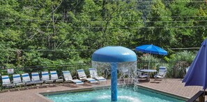 Une piscine agrémentée d’une fontaine, de chaises longues et de parasols.