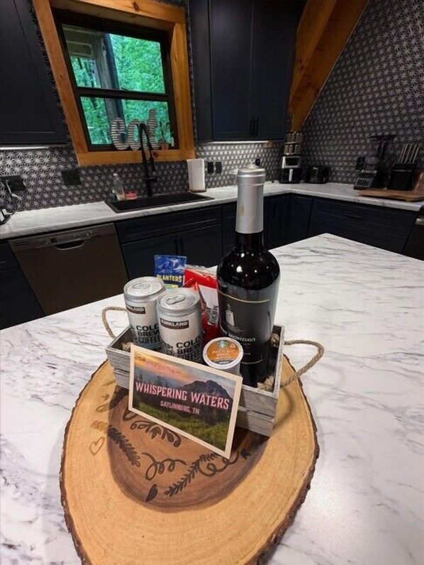 Une cuisine avec des meubles de couleur sombre, un plan de travail en bois et une fenêtre donnant sur un paysage verdoyant.