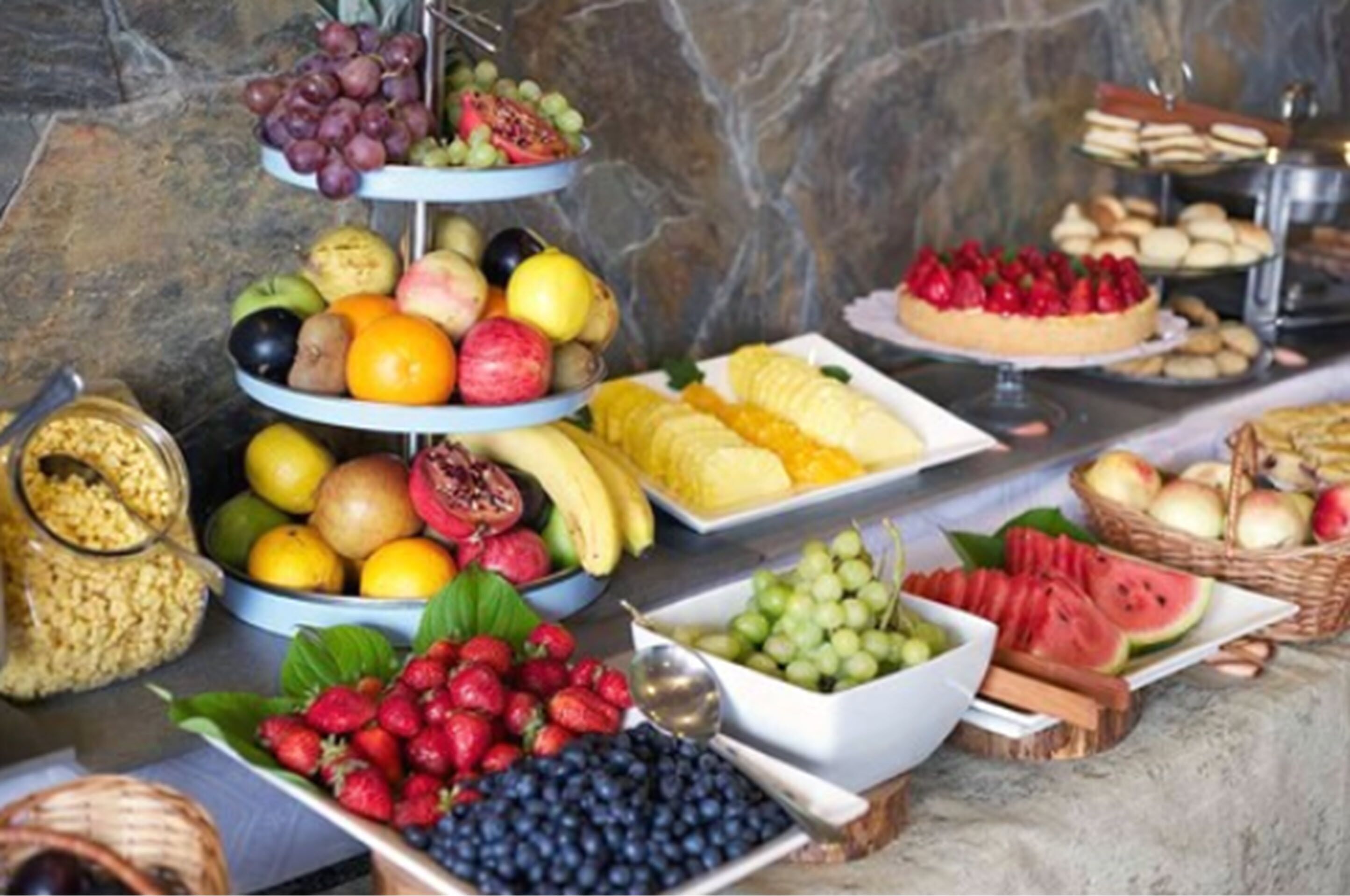 Un bufé con diversas frutas y pasteles.
