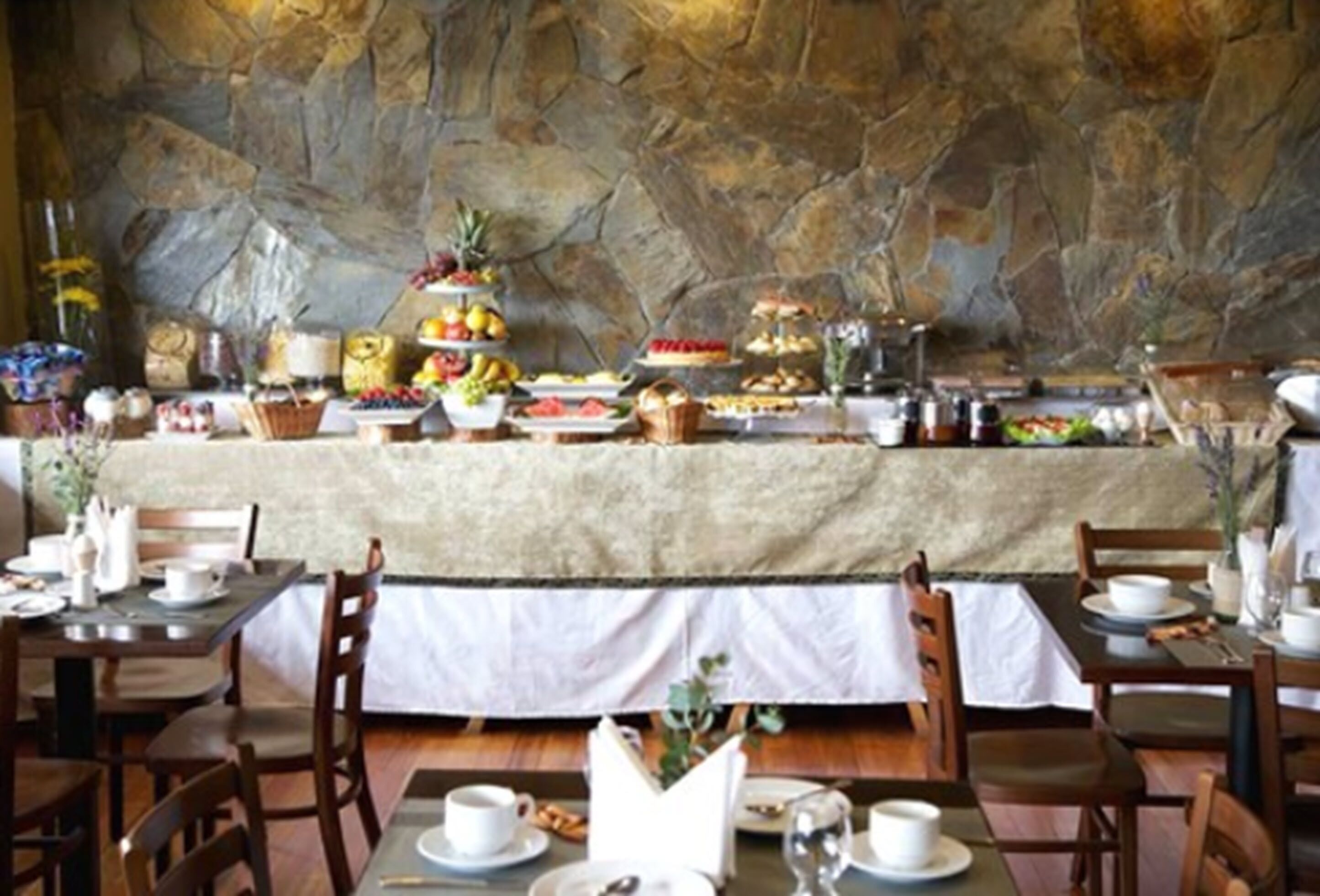 A buffet setup with various food items and a stone wall backdrop.