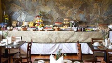 A buffet setup with various food items and a stone wall backdrop.