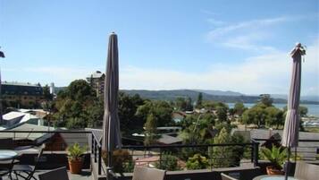 Una terrazza esterna con tavoli e sedie, ombrelloni e vista sulla città e le colline.