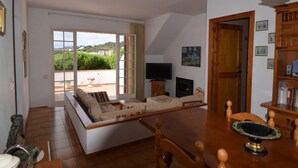 A living room with a sofa, a TV, and a dining table. - Voramar CostaBravaSi - Pool, BBQ, views, wifi (S'Agaró)