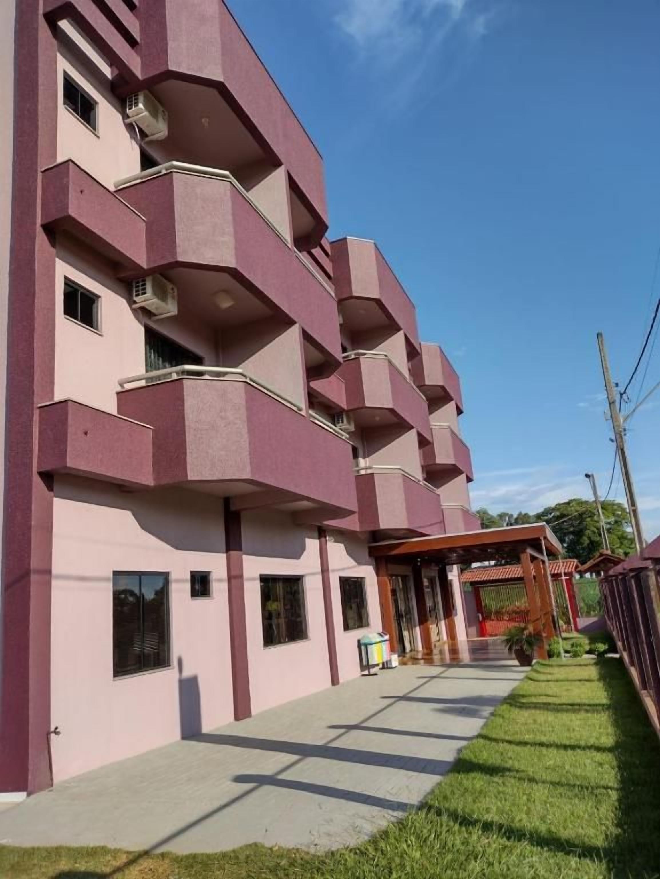 A multi-story building with balconies, a covered entrance, and a well-maintained lawn.