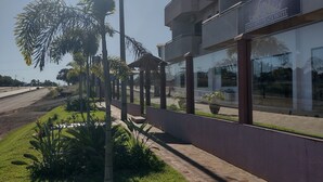 A hotel with a modern design, featuring a glass facade and a well-maintained outdoor area with grass and plants. - Conforto Plaza Hotel (Capitão Leônidas Marques)